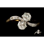 AN ANTIQUE TWO STONE DIAMOND CROSS OVER RING, to diamond shoulders,