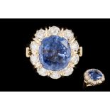 A SAPPHIRE AND DIAMOND CLUSTER RING, the cushion cut sapphire weighing 7.