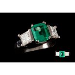 AN EMERALD AND DIAMOND THREE STONE RING, mounted in platinum, estimated weight of emerald :1.