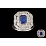 A SAPPHIRE AND DIAMOND CLUSTER RING, a rectangular step cut sapphire of 2.