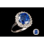 A SAPPHIRE AND DIAMOND CLUSTER RING, a cushion cut sapphire of 5.82ct with gem report, and