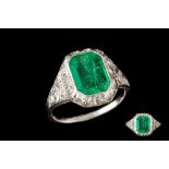 AN EARLY 20TH CENTURY EMERALD AND DIAMOND CLUSTER RING, one emerald of approx 1.