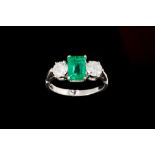 AN EMERALD AND DIAMOND THREE STONE RING, with one rectangular step cut emerald of 1.