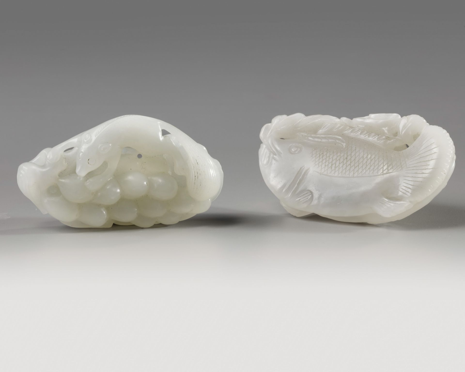 A Chinese white jade ‘squirrel and grapes’ carving and a white jade ‘twin fish’ carving