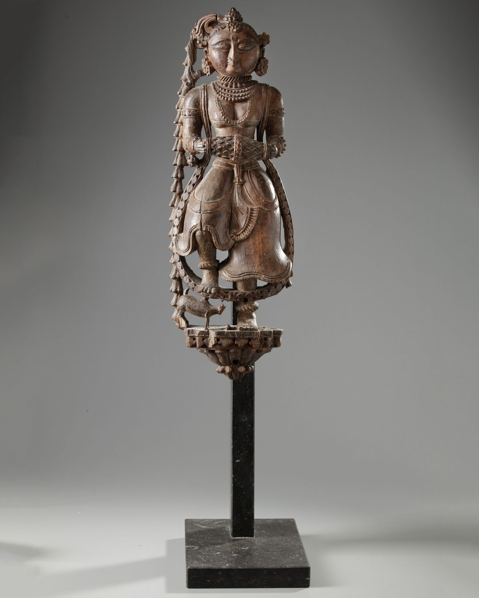 An Indian wood sculpture of a lady on a marble stand