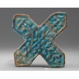 An Islamic turquoise cross shaped tile