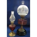 Late Victorian brass double burner oil lamp with cranberry glass reservoir, ceramic base,