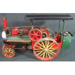 Live steam scale model of a two cylinder steam traction engine on green livery with black canopy.