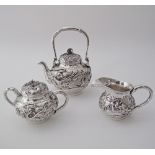 A Chinese silver three piece tea set with dragon decorations and simulated bamboo handles, the tea