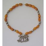 An amber and white metal necklace with a center pendant L60cm.