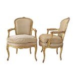 A pair of Louis XV style fauteuils, carved, gessoed and gilt, in beige upholstery, late 19th / early