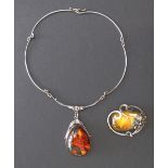 A Russian amber pendant L40mm and pin brooch L45mm, set in white metal. (2)