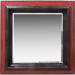 An American modern mirror, framed and upholstered in red and brown leatherette, with brass studding.