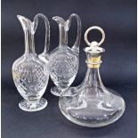 A pair of crystal pitchers and one decanter with a white metal stopper