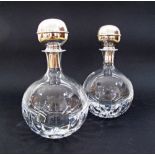 A pair of hand-cut spherical crystal decanters with sterling silver stoppers.