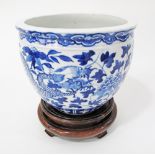 A Chinese blue and white porcelain fish bowl with dragon and leaf decoration on hardwood stand