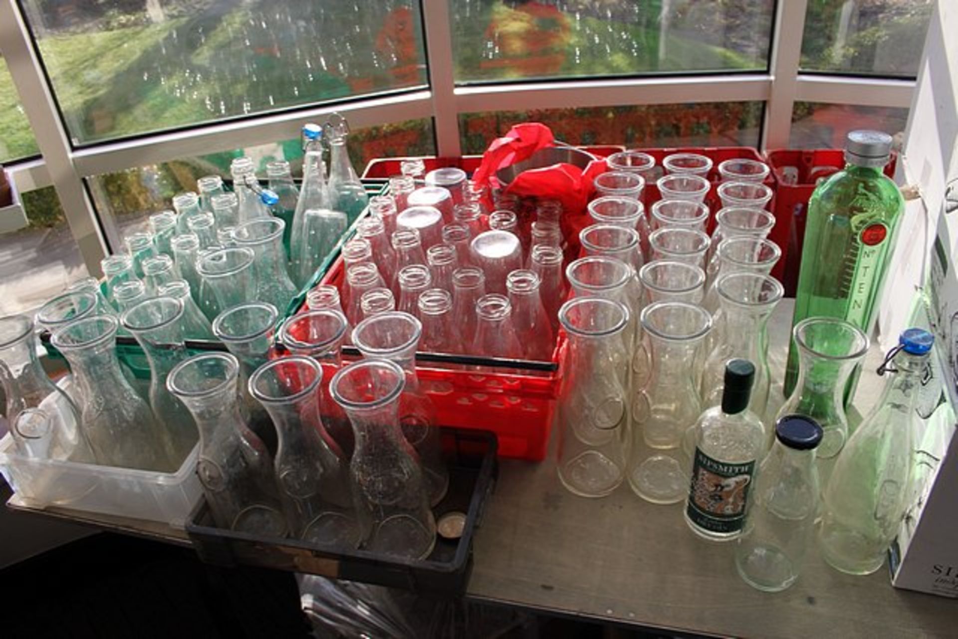 A large quantity of glass bottles used as water and wine carafes comprising of old style milk