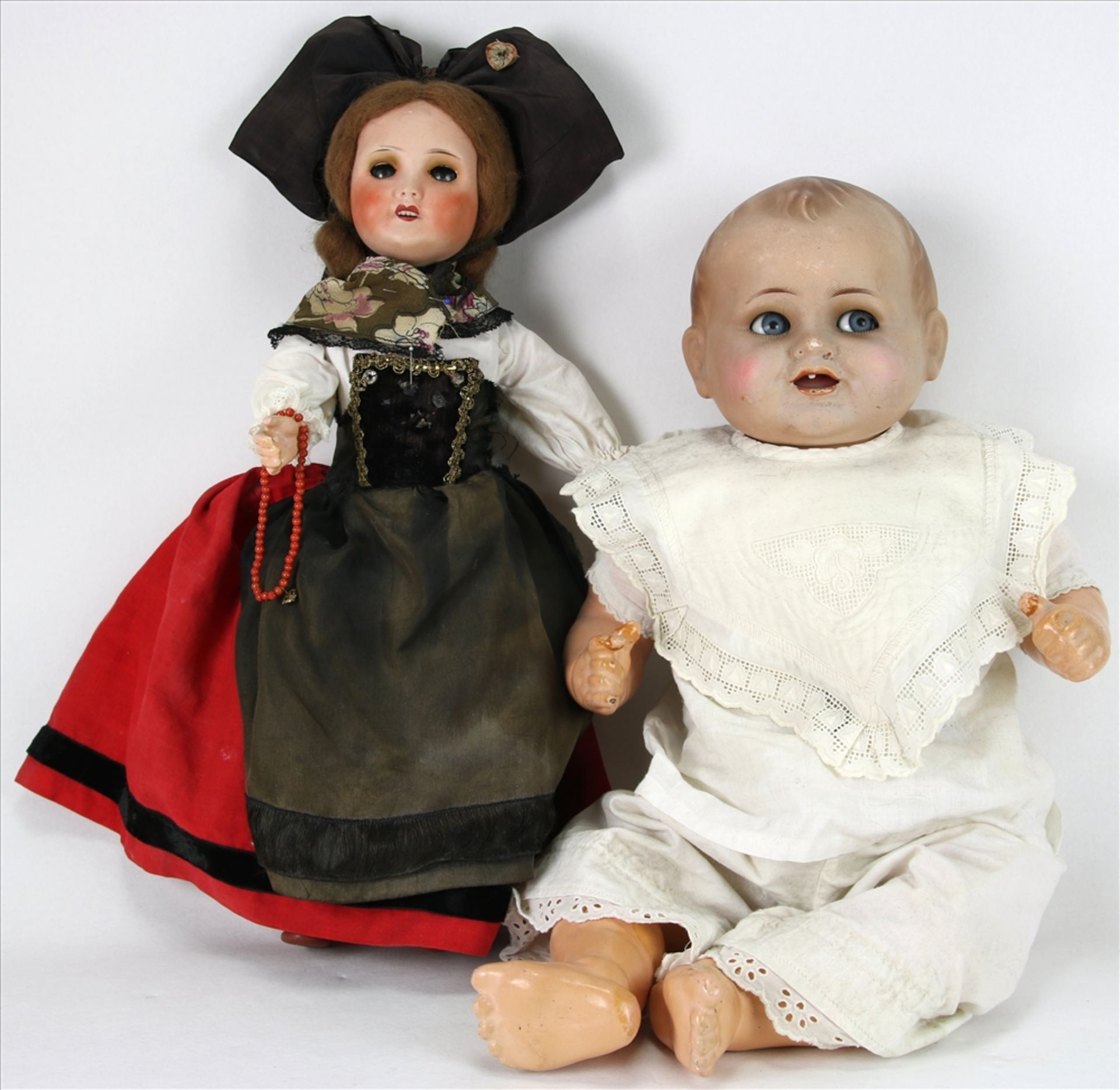 Zwei Puppen Thüringen um 1900. Puppenbaby mit Kopf aus Hartplastik mit offenem Mund und einem