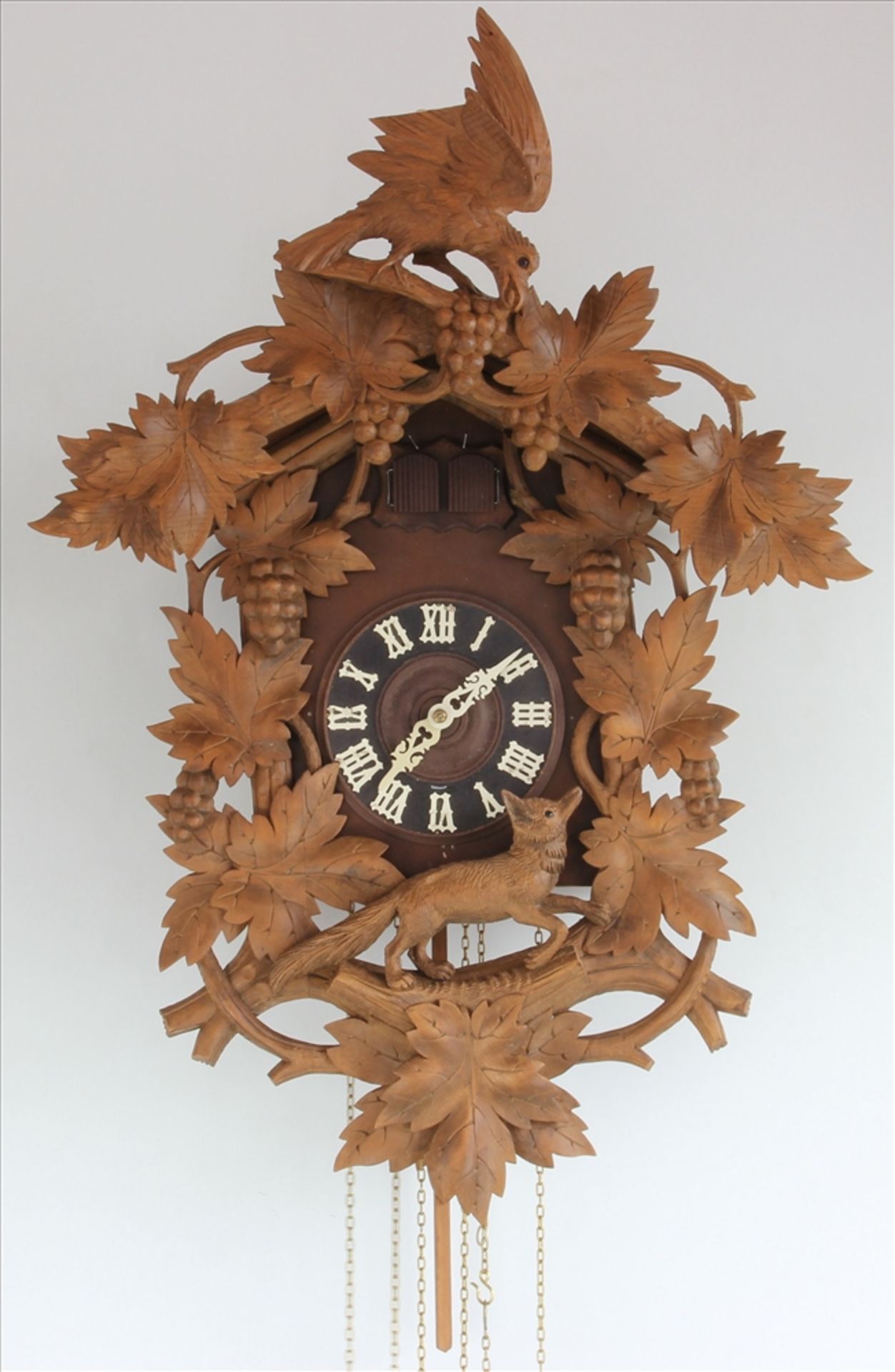 Kuckucksuhr Um 1900. Holzgehäuse mit floralen und jagdlichen Applikationen. Messingräderwerk mit