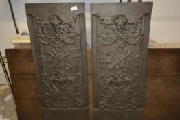 A pair of large cast-iron panels, in the Elizabethan taste, each with female mask above a trophy