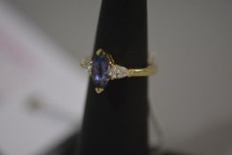 A tanzanite and diamond three stone ring, the central marquise-cut tanzanite flanked by a pair of