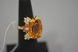 A citrine, diamond and ruby dress ring, the large citrine of cushion shape within a border of claw-