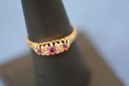 A late Victorian diamond and ruby ring, set with three graduated rubies spaced by two pairs of old