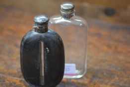 Two Victorian silver-topped glass hip flasks, the first encased in black leather, the screw top