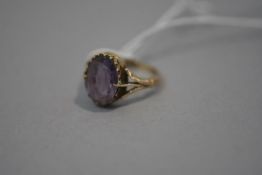 A late 19th century amethyst single stone ring, the oval-cut stone claw set over split shoulders