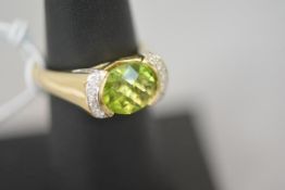 A peridot and diamond ring, the oval mixed-cut peridot flanked by twin bands of round brilliant-