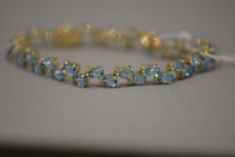 A topaz and diamond bracelet, the paired pear-cut stones spaced by diamond points, mounted in yellow