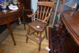 A 19th century elm child's high chair, of Windsor type, the back with spindle and baluster carved