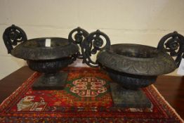 A pair of late 19th century cast-iron garden urns, each with boldly scrolled leaf and flowerhead-