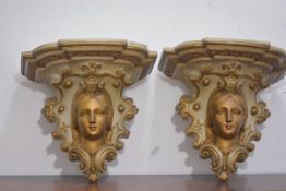 A pair of parcel-gilt plaster wall brackets, c. 1900, each with shaped shelf above a female mask