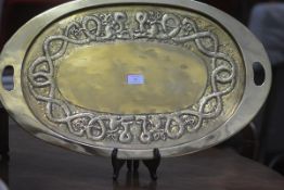 A Scottish Arts & Crafts brass tray, oval, repousse to the well with entwined serpents. Across