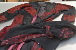 A Palestinian evening coat in black with red needlework; together with a black shawl with similar