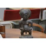 A large African tribal carved wooden figure, probably West African, the seated male with prominent