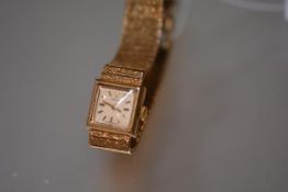 A lady's Longines 9ct gold wristwatch, the square silvered dial with baton numerals, on a 9ct gold