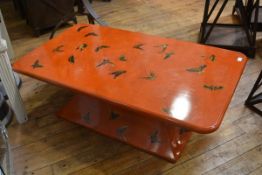A Fornasetti style lacquered coffee table, decorated with butterflies against a mottled orange