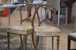 A pair of Victorian walnut drawing room chairs, each with scroll carved double arch back, raised