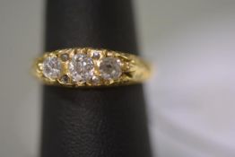 An early 20th century three stone diamond ring, the graduated round brilliants spaced by two pairs