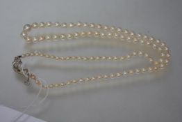 A vintage single strand cultured pearl necklace on a diamond clasp, the seven stone flowerhead clasp