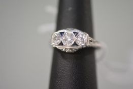 A three-stone diamond ring, in the Art Deco taste, the graduated round brilliants in hexagonal rub-