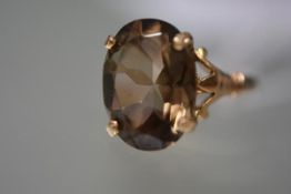 A large smoky quartz single stone ring, the oval stone claw-set on split shoulders and a tapering