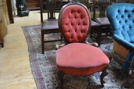 A Victorian walnut framed spoon back nursing chair, the oval back with floral carved crest over a