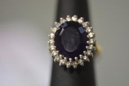 An amethyst and diamond ring, the large oval step-cut amethyst claw-set within a band of twenty-