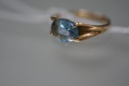 A single stone blue topaz ring, the oval cut stone set on a fluted tapering 9ct yellow gold band.