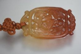 A Chinese russet jade pendant, the panel pierced and carved as a bird, on a silk neck chain. Pendant