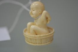 A Japanese ivory netsuke, carved as a child washing in a tub, seal mark to base. 40mm