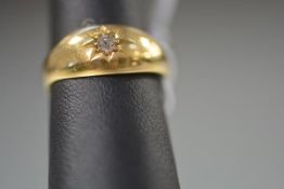 An Edwardian 18ct yellow gold diamond ring, the gypsy-set brilliant-cut stone on a tapering band.